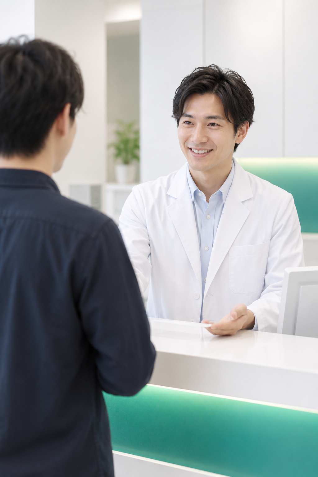 予約日時に来院した患者を受付で迎える男性スタッフ